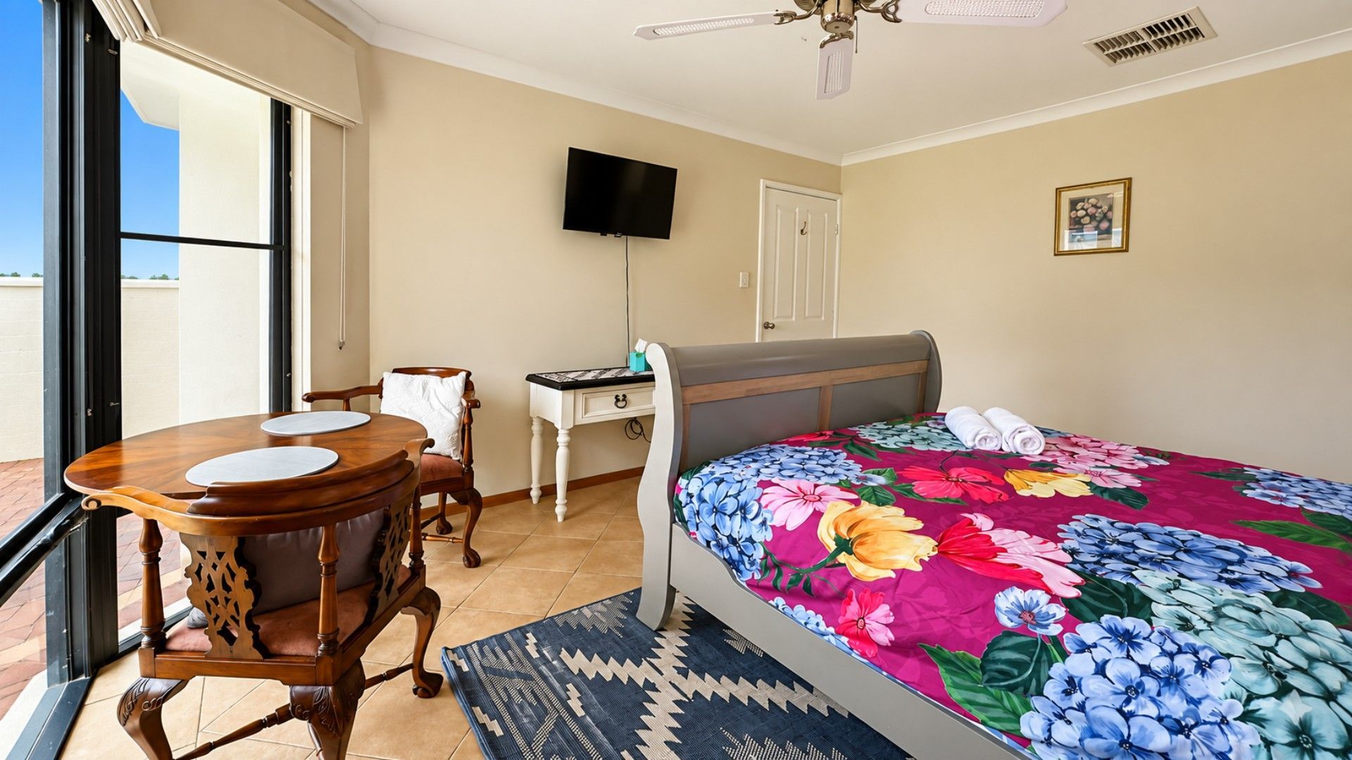 Een hotelkamer met een bed, een bureau, een stoel, een televisie en uitzicht door een raam.