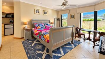 A bedroom with a bed, bedside tables, a desk, and a chair. There is a view of the outside through a window.