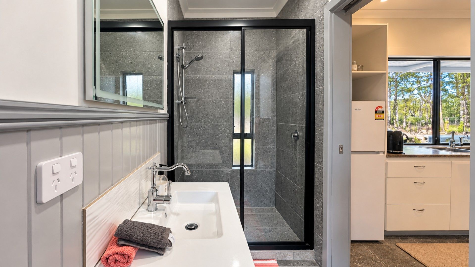 A modern bathroom with a shower, a sink, and a mirror.