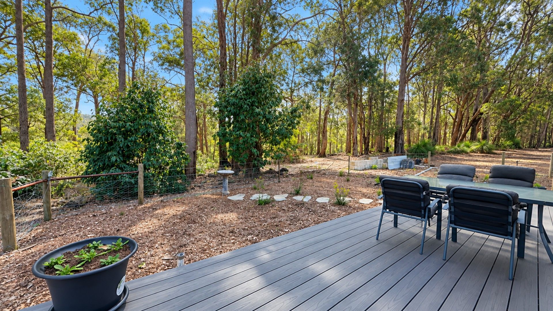 An outdoor deck with a table and chairs, surrounded by a wooded area.