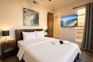 Una habitación de hotel con una cama grande, un cuadro, un televisor y vistas a la playa.