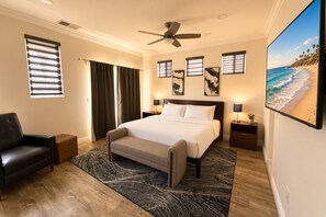 A bedroom with a bed, a chair, a ceiling fan, a nightstand, a lamp, and a beach view. - Pacific Beach: Private Backyard, BBQ, Garage, AC (San Diego)