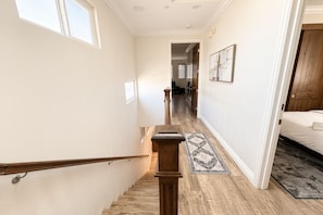 A staircase leading to a bedroom with a wooden floor, a rug, and a painting on the wall. - Pacific Beach: Private Backyard, BBQ, Garage, AC (San Diego)