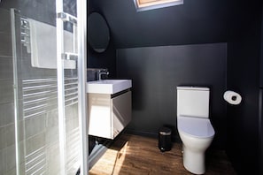 Ein kleines Badezimmer mit Toilette, Waschbecken und einem kleinen Mülleimer.
