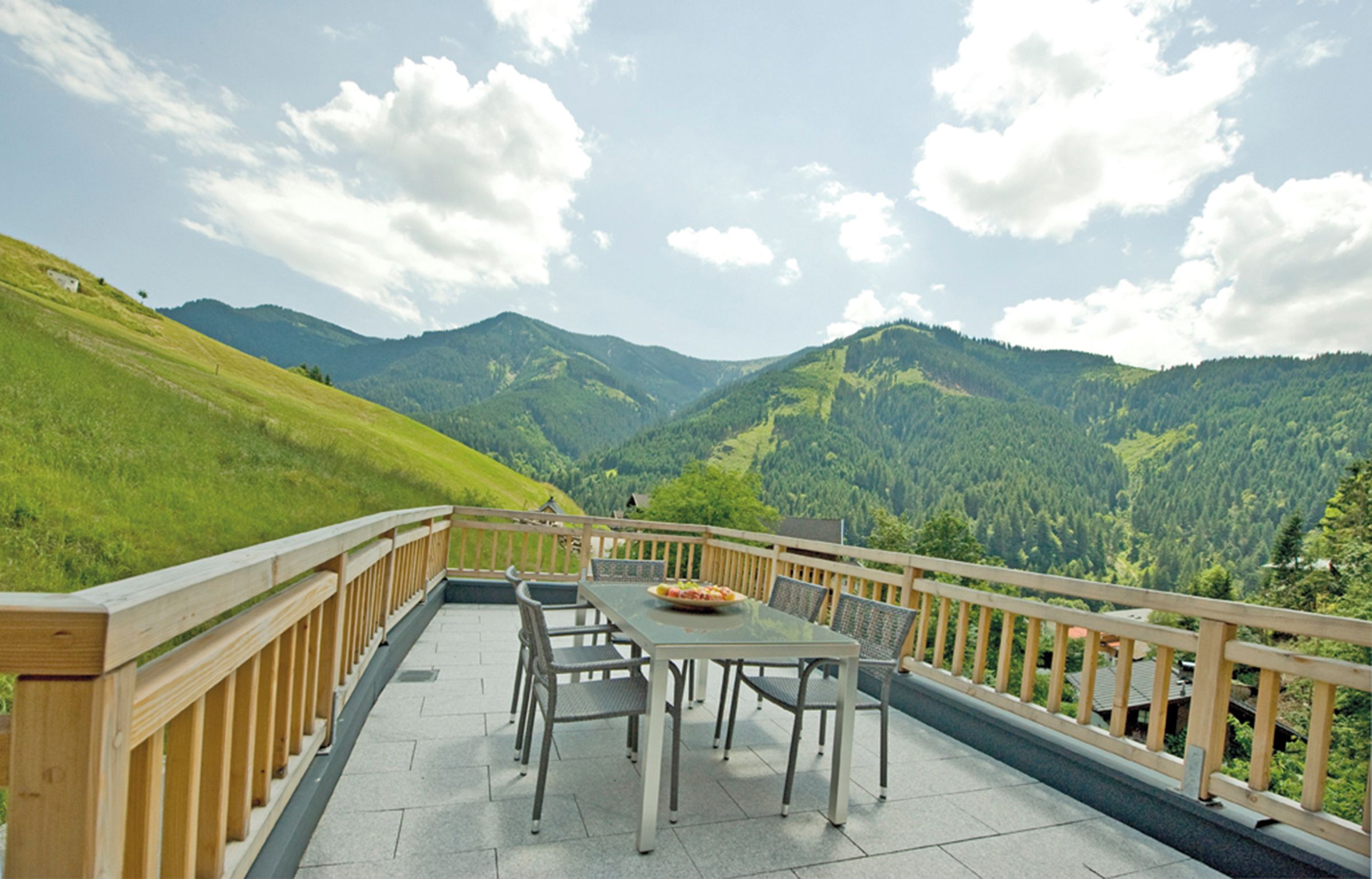 A terrace with a table and chairs overlooking a mountainous landscape.