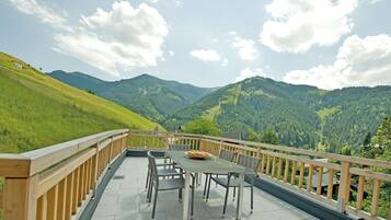 A terrace with a table and chairs overlooking a mountainous landscape.