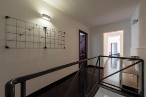 A modern interior with a staircase, a wall-mounted light fixture, and a door leading to another room. - Living Filomarino - Studio 3 (Naples)