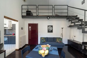 A modern loft-style living space with a kitchen, dining area, and a staircase. - Living Filomarino - Studio 3 (Naples)