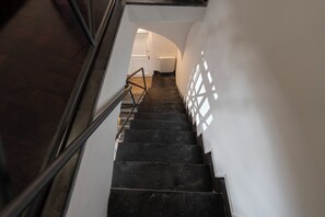 A staircase with a handrail, leading to a room with a white door and a radiator. - Living Filomarino Collection (Naples)
