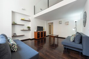 A modern living room with a flat-screen TV, wooden cabinets, and a glass coffee table. - Living Filomarino Collection (Naples)