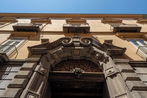 Eine Gebäudefassade mit aufwendigen architektonischen Details, darunter ein zentrales Zierteil und mehrere Fenster.