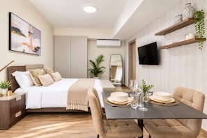 A modern bedroom with a bed, bedside table, and a dining area with chairs and a table. - Harmonia 1118 (Accra)