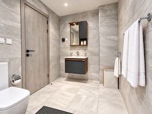 A modern bathroom with a toilet, sink, and shower area. - Harmonia 1118 (Accra)