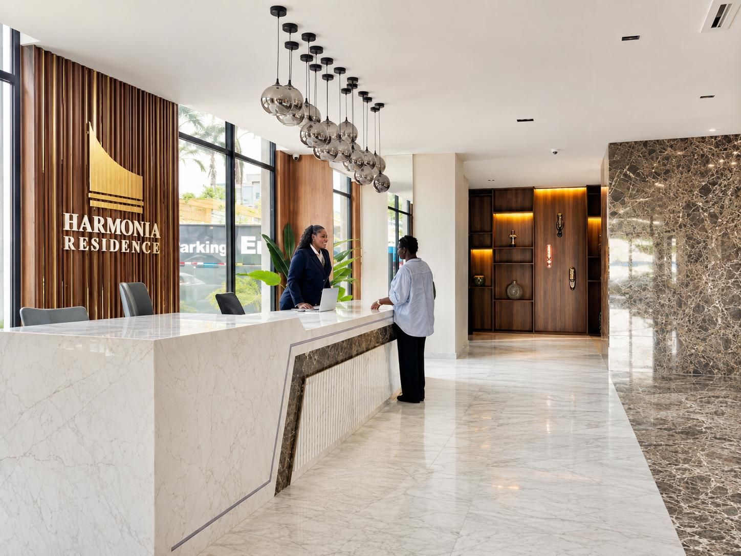 A hotel reception area with a marble reception desk, a wooden wall with the hotel name, and a modern chandelier.