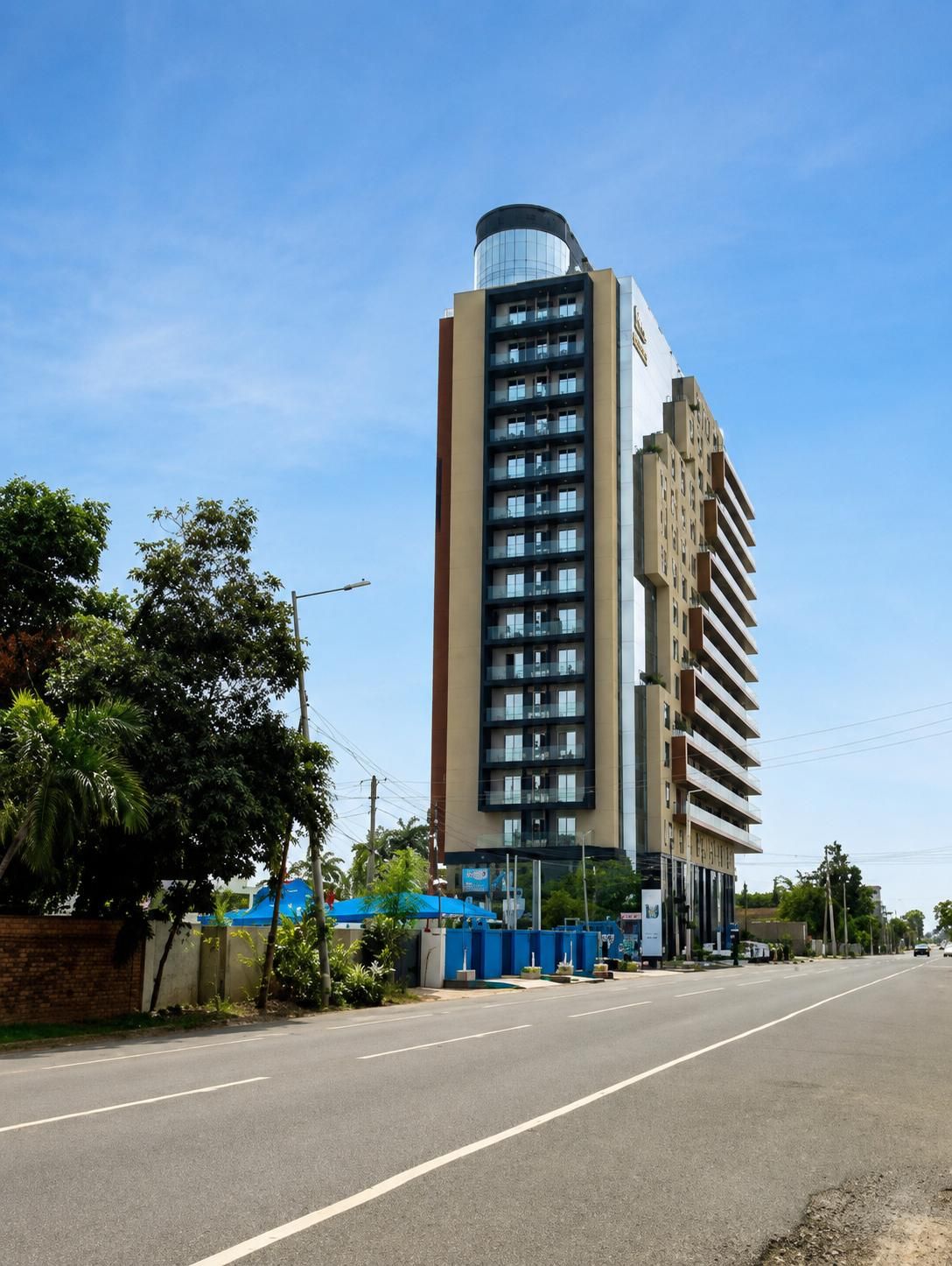 A multi-story building with a curved glass facade, a flat roof, and a series of balconies.