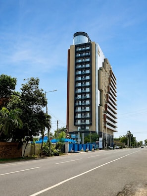A multi-story building with a curved glass facade, a flat roof, and a series of balconies. - Harmonia 1118 (Accra)