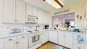 A kitchen with white cabinets, a microwave, a stove, and a dishwasher. - Bethany Bay - 4903 Pettinaro Dr. (Ocean View)
