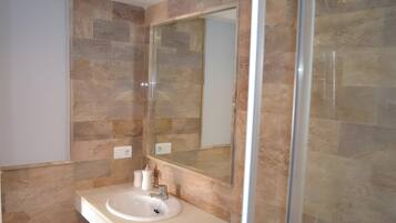 A bathroom with a white sink, a mirror, and stone tiles.