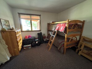 A room with a bunk bed, a dresser, a window with blinds, and a ladder. - Recreation & relaxation from your vintage Yellowstone style cabin in Absarokee! (Absarokee)