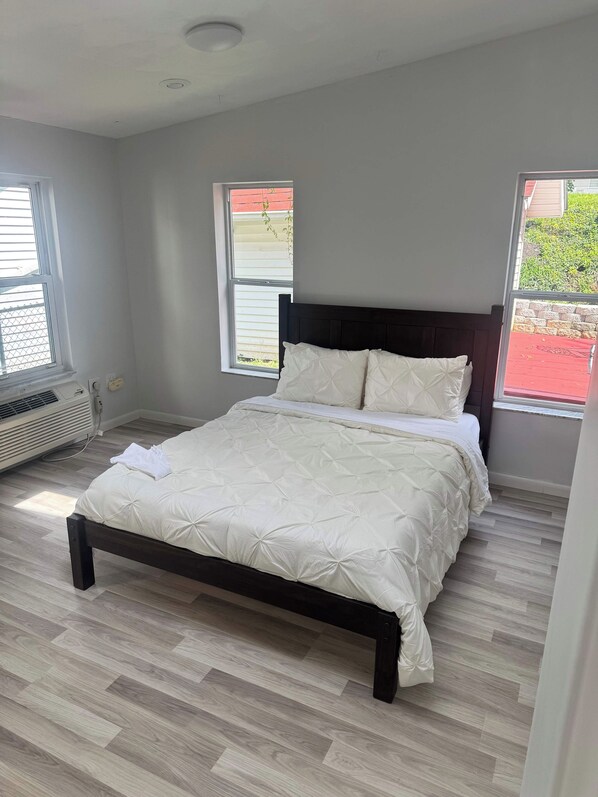A bedroom with a bed, two windows, and a radiator.