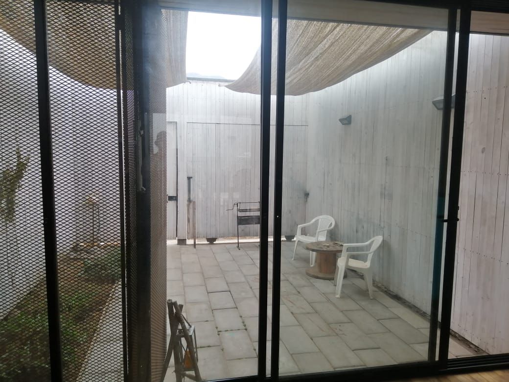 Un espacio al aire libre techado con un conjunto de asientos y una parrilla.