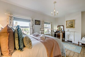 Ein Schlafzimmer mit einem Bett, einem Kamin und Blick ins Freie.