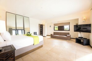 Ein Hotelzimmer mit Bett, Sofa, Fernseher und Schreibtisch.