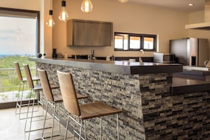 Une cuisine moderne dotée d’un bar, de tabourets de bar et offrant une vue sur l’extérieur.