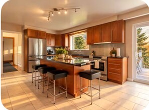 A modern kitchen with a central island, bar stools, stainless steel appliances, and wooden cabinets. - Gorgeous 3-bedroom cottage in Mono for a relaxing stay on a conservation area (Mono)
