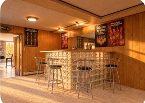 A bar area with a counter and four stools, wooden walls, and posters on the wall. - Gorgeous 3-bedroom cottage in Mono for a relaxing stay on a conservation area (Mono)