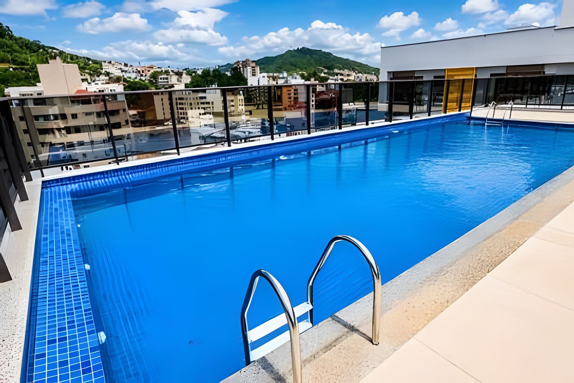A swimming pool with clear blue water, surrounded by a modern building with glass railings.