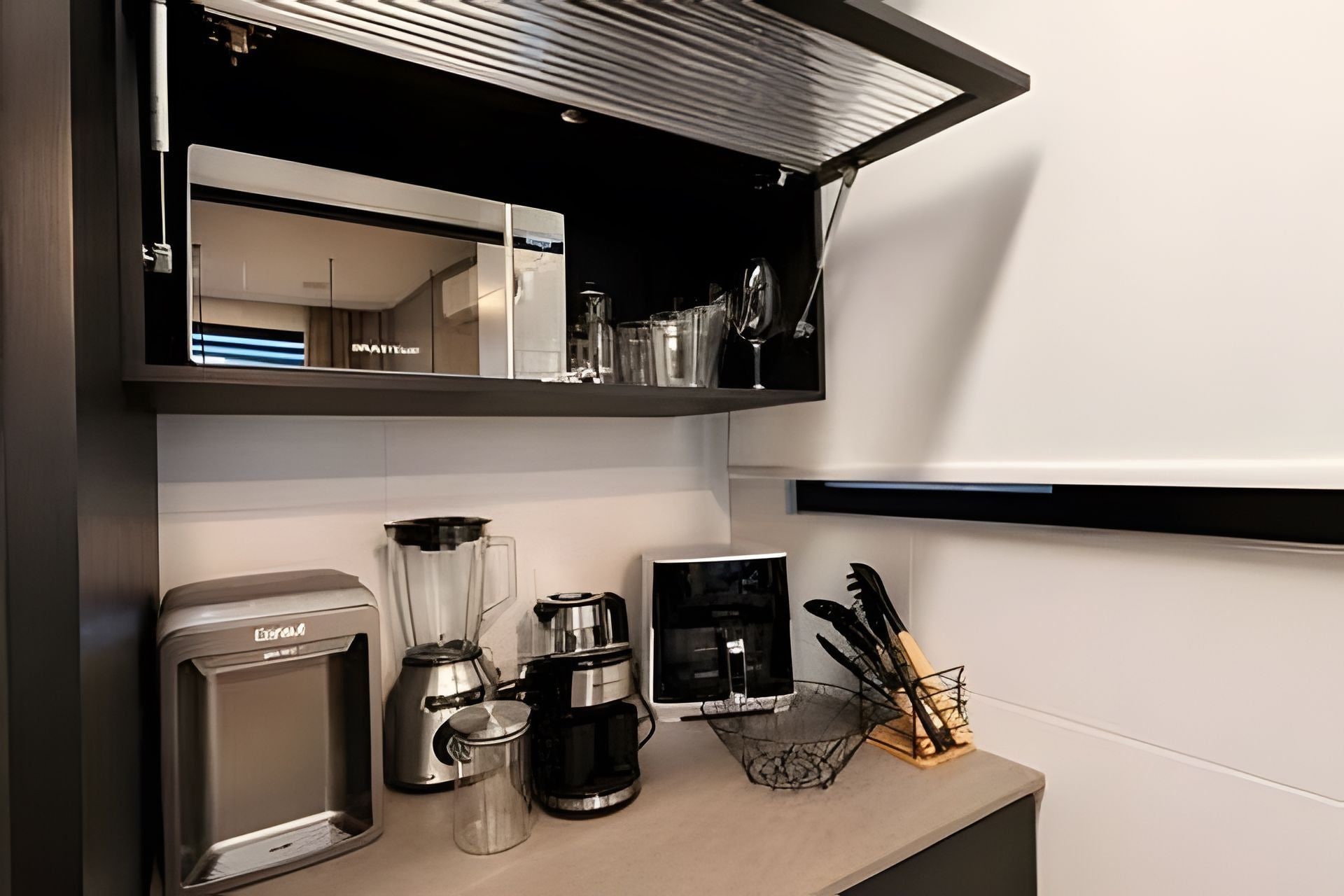 Una cocina con cafetera, licuadora y hervidor sobre la encimera.