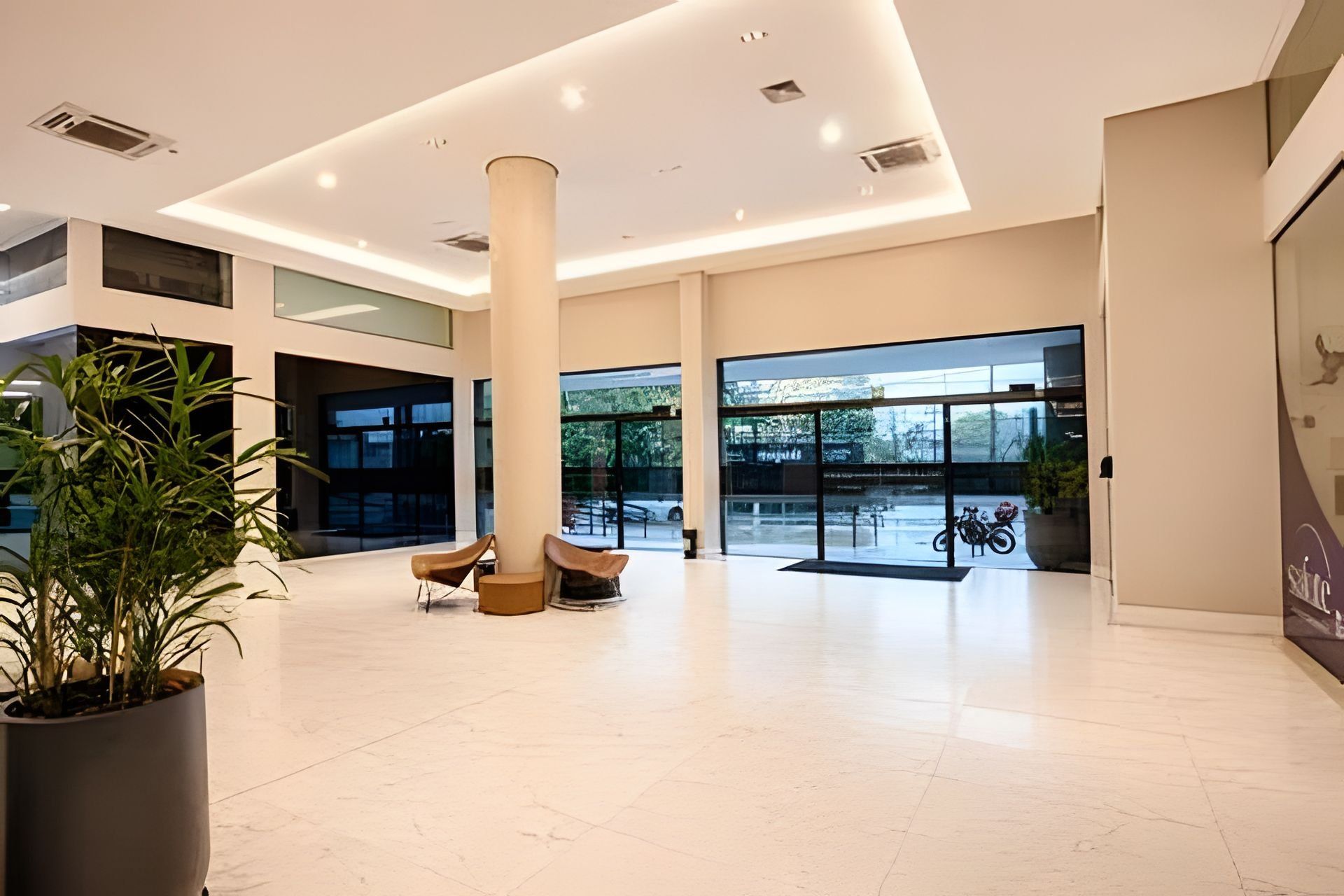 Eine geräumige Lobby mit hoher Decke, großen Fenstern und einer zentralen Säule.