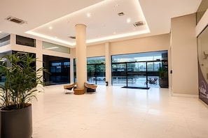 A spacious lobby with a high ceiling, large windows, and a central column.