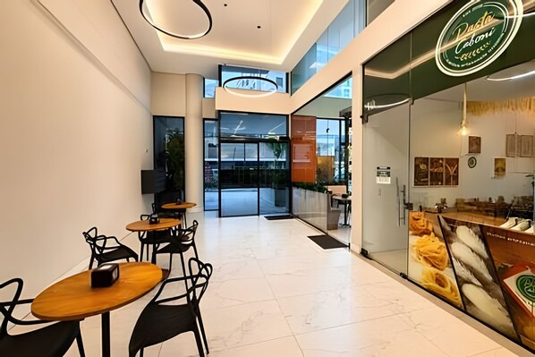 A modern cafe interior with tables and chairs, a large window, and a cafe sign. - Studio em ultimo andar linda vista (Florianópolis)