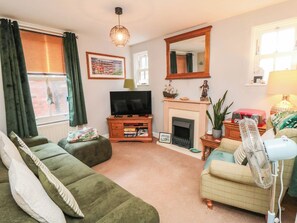 A living room with a green sofa, a television, a fireplace, and a mirror. - Pirates Berth (Whitby)