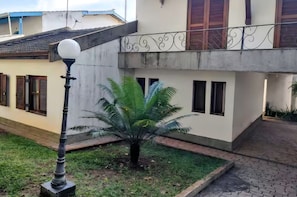 A courtyard with a lamp post, a small palm tree, and a building with windows and a balcony. - Complete property with access to the reservoir, pets allowed. (Atibaia)