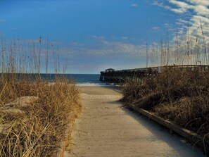 A sandy path leading to a wooden pier extending into the water. - Oceanfront 3BR  Balcony Bliss!  Park Close to Your Door (Myrtle Beach)