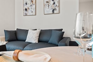 Una sala de estar moderna con un sofá gris, un cojín blanco estampado y arte abstracto en la pared.
