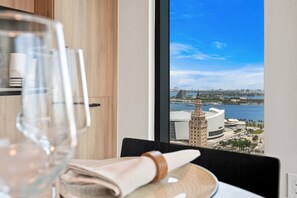 Una mesa de comedor con un vaso de agua y una servilleta, una ventana que ofrece vistas a un paisaje urbano y al agua.