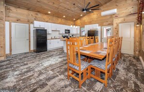 A spacious kitchen with wooden cabinets, a central island, and a dining area with wooden chairs. - Cozy Glamping Cabin #3 in Swanton (Swanton)