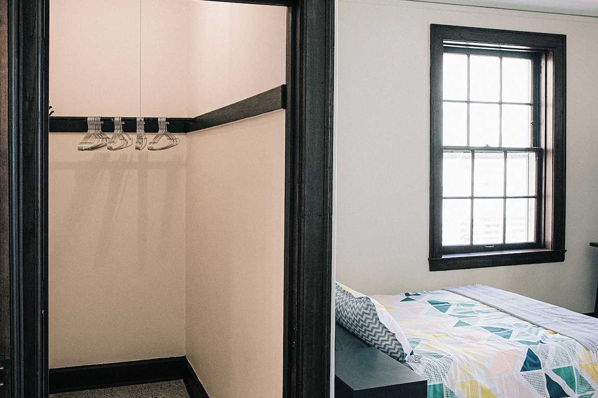 A bedroom with a bed, a window, and a door leading to a bathroom.