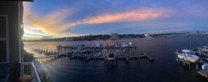 A marina with boats docked, a bridge in the background, and a sunset. - Palm Court Yacht Club 604 (Fort Walton Beach)