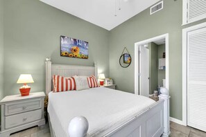 A bedroom with a bed, nightstands, lamps, and a wall art piece. - Palm Court Yacht Club 604 (Fort Walton Beach)