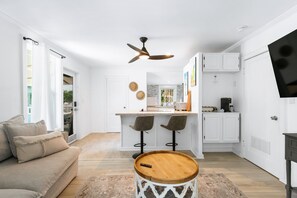 A modern kitchen with a central island, bar stools, and a ceiling fan. - Cozy 1-bedroom Apartment Suite+ Pool & Hot Tub (Key West)