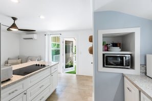 Eine moderne Küche mit integriertem Mikrowellenherd, Deckenventilator und Blick ins Freie.