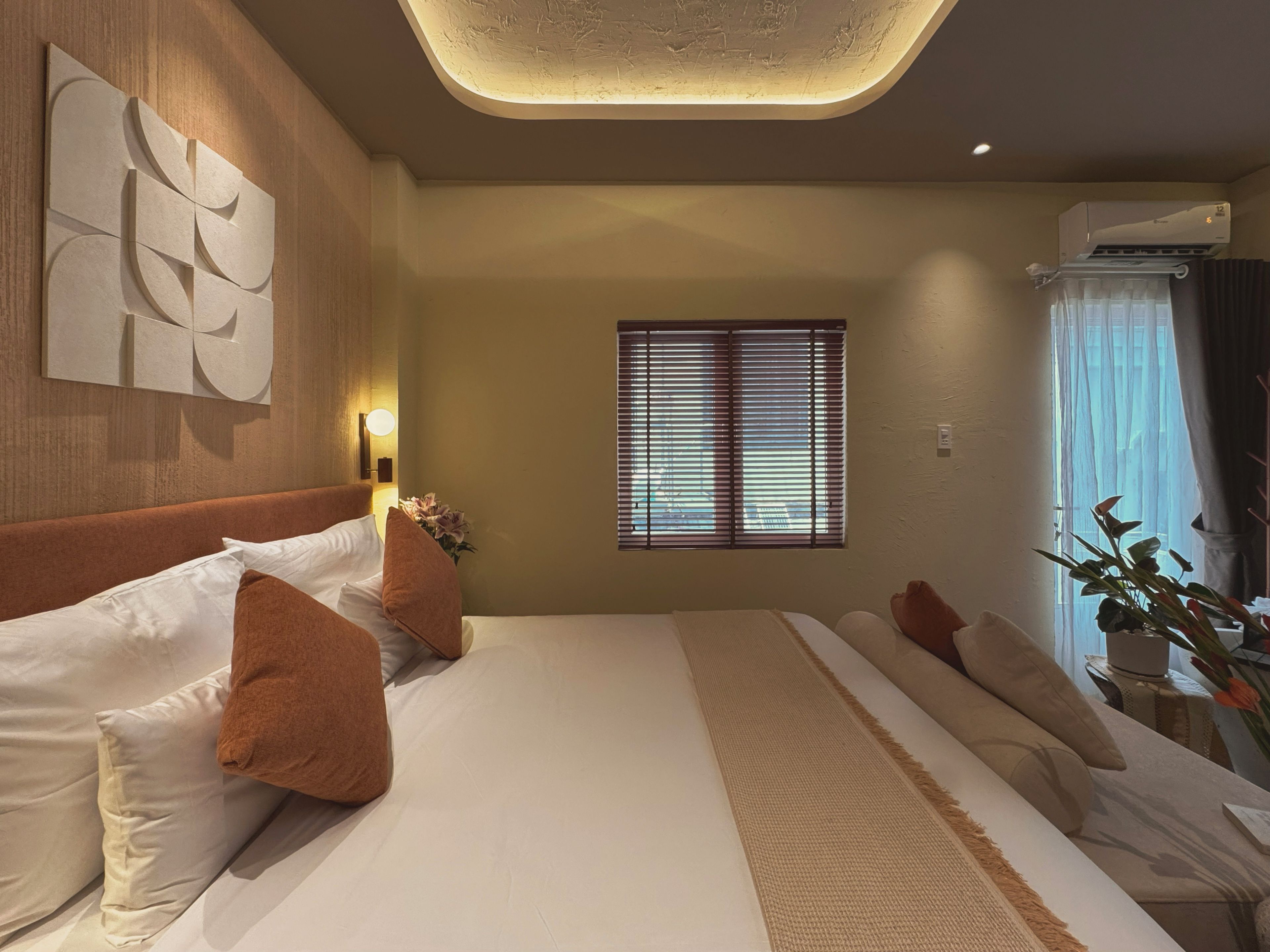 Habitación de hotel con una cama grande, una obra de arte en la pared, una ventana con persianas y un equipo de aire acondicionado.