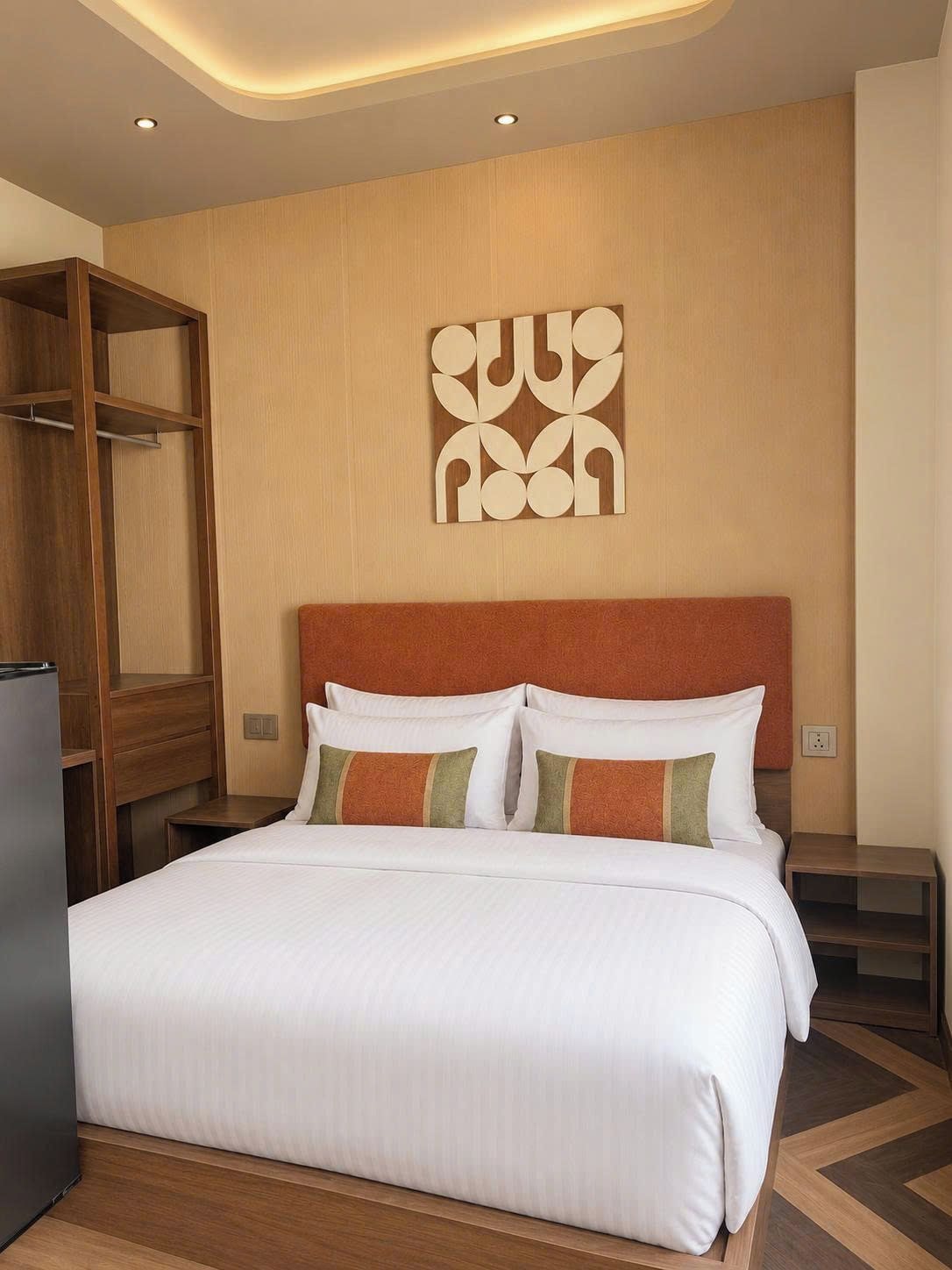 Habitación de hotel con cama, armario de madera y un adorno en la pared.