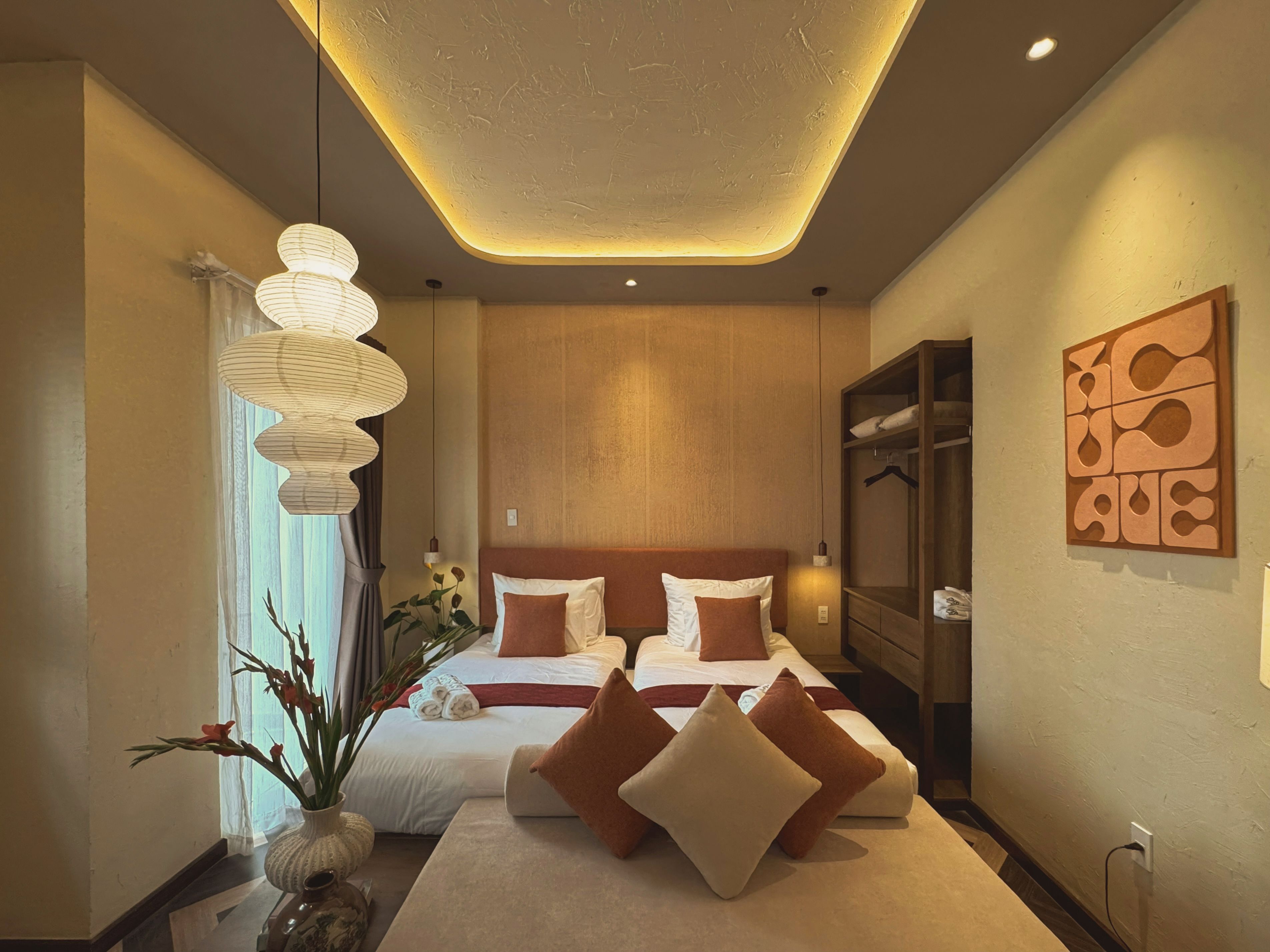 Une chambre d’hôtel moderne dotée d’un grand lit, de tables de chevet, d’une armoire et d’un luminaire au plafond au design original.