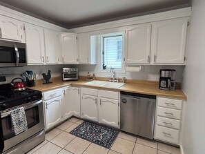 A kitchen with white cabinets, a stainless steel stove, a microwave, a toaster, and a coffee maker.